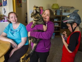 Maureen O'Malley watches as her daughter, Maddy, holds the family cat while her son, Marlon, checks out her phone at their home Coquitlam.