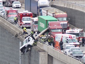 Emergency crews and tow-truck workers tend to a truck hanging over an embankment on Highway 17 near the Surrey/Delta border on Thursday.