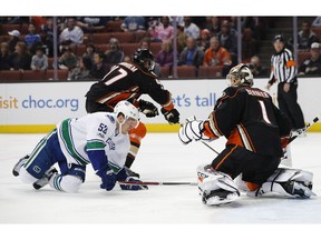 Anaheim Ducks' Hampus Lindholm, top left, takes the puck away from Vancouver Canucks' Bo Horvat in front of Ducks goalie Jonathan Bernier during the first period of an NHL hockey game Sunday, March 5, 2017, in Anaheim, Calif.