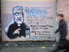 man walks past a mural by street artist Smokey D. about the fentanyl and opioid overdose crisis, in the Downtown Eastside.