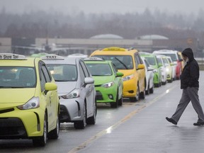 A taxi driver walks back to his cab while waiting for passengers at Vancouver airport at Richmond in March.