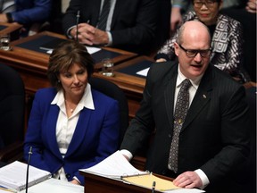 B.C. Finance Minister Mike de Jong, with Premier Christy Clark watching, announces as part of the province’s budget that Medical Services Plan premiums will be cut by 50 per cent for most resident households.