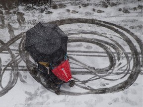 A person in a wheelchair pauses on a sidewalk as snow falls in Vancouver.