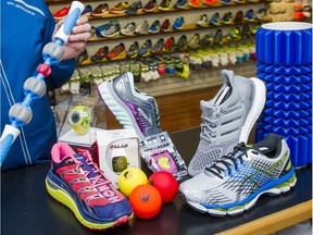 SURREY, BC: February 29, 2016 -- Paul Williams holding an Addaday massage bar displays from left to right Hoka-Speedgoat shoes, a Timex Run sports watch, a Polar M400 running watch, Brooks Glycerin shoes,  a trio of massage balls, Nathan reflective laces, Adidas Ultra Boost shoes, Asics Nimbus shoes and an Addaday massage roller at Peninsula Runners in South Surrey Monday February, 29, 2016.  (photo by Ric Ernst / PNG)  (Story by Tiffany Crawford)  TRAX #: 00041953A [PNG Merlin Archive]