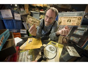 Brian Grant Duff examines a $25 bank note (celebrating King George's jubilee) along with a 1859 $4 bill which are being auctioned by All Nations Stamp and Coin.