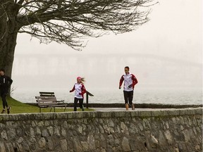 Morning rain does not stop joggers from running on the seawall around Vancouver's Stanley park.