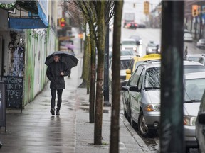 A pedestrian 'enjoys' a lonely walk as the rain pelts down in downtown Vancouver on Tuesday.