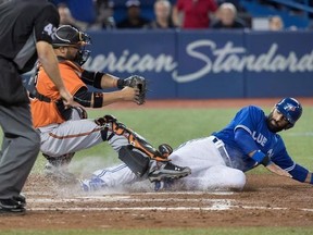 Toronto Blue Jays&#039; Jose Bautista scores getting his foot on home plate before Baltimore Orioles catcher Welington Castillo can come down with the tag in the seventh inning of AL baseball action in Toronto on Saturday April 15, 2017. THE CANADIAN PRESS/Fred Thornhill