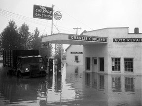 Two men in a partially submerged truck peer over at a Chevron gas station and the Charlie Copland Auto Repair shop in Mission that appears to be closed in 1948.