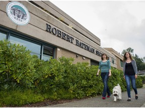 Danae Hodgins, left, and Lindsey Byrnes take wheaten terrier Chewie for a walk outside Robert Bateman Secondary school.
