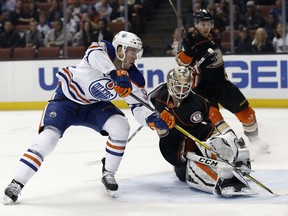 In this Wednesday, March 22, 2017, photo, Edmonton Oilers center Connor McDavid, left, scores against Anaheim Ducks goalie Jonathan Bernier, center, with defenseman Cam Fowler, right, watches during the first period of an NHL hockey game in Anaheim, Calif. The NHL's coaching carousel is paying off for playoff-starved franchises in Toronto, Edmonton and Columbus. With the season wrapping up on Sunday, the Maple Leafs' Mike Babcock, Oilers' Todd McLellan and Blue Jackets' John Tortorella have emerged as coach of the year candidates.