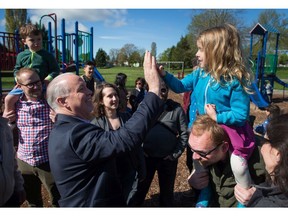 NDP Leader John Horgan high-fives a young girl during a campaign stop at a park in Vancouver on Sunday.