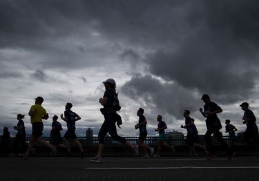 Runners are silhouetted as they cross the Cambie Bridge during the Sun Run in Vancouver, B.C., on Sunday April 23, 2017.