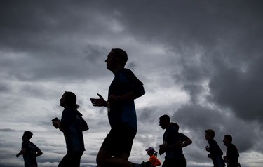 Runners are silhouetted as they cross the Cambie Bridge during the Sun Run in Vancouver, B.C., on Sunday April 23, 2017.