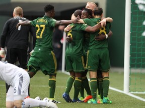 Teammates swarm Portland Timbers' Darren Mattocks following his first-half goal during an MLS soccer game against the Vancouver Whitecaps, Saturday, April 22, 2017, in Portland, Ore.