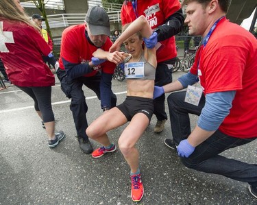 Lindsay Carson is helped up after crossing the finish line as about 40,000 runners competed in 2017 Vancouver Sun Run in Vancouver, B.C., April 23, 2017.