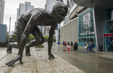 People walk past the Percy Williams statue towards the 2017 Vancouver Sun Run in Vancouver, B.C., April 23, 2017.