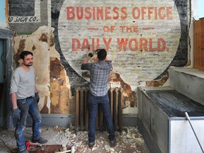 Shawn Pisio, right, and Michael Broadbent at work in a building where a ghost sign for The Vancouver Daily World newspaper has just been rediscovered on a wall during renovations at 343 W. Pender St. on Wednesday.