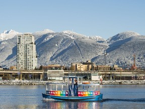 An Aquabus makes its way through the waters of False Creek with the snow caped North Shore Mountains providing a backdrop to the morning ride in Vancouver at day break, Dec., 6, 2016.