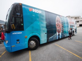 A woman poses next to British Columbia NDP Leader John Horgan's election campaign bus.