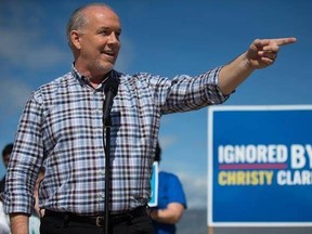 NDP Leader John Horgan gestures while standing in front of a sign reading &ampquot;Ignored By Christy Clark&ampquot; during a healthcare related campaign stop in Kamloops, B.C., on Tuesday May 2, 2017. A provincial election will be held on May 9. THE CANADIAN PRESS/Darryl Dyck