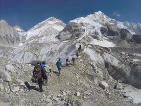 FILE - In this Feb. 22, 2016 file photo, international trekkers pass through a glacier at the Mount Everest base camp, Nepal. A Nepalese official says Sherpa workers are fixing the final route to the summit of Mount Everest and the first climb of the season could be days away. (AP Photo/Tashi Sherpa, file)