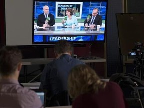 Reporters watch the British Columbia election leadership live radio debate with NDP Leader John Horgan, Liberal Leader Christy Clark and Green Party Leader Andrew Weaver on a television in Vancouver on April 20, 2017. The fate of the $7.4-billion Trans Mountain expansion could rest on the outcome of two B.C. election recounts to take place from Monday to Wednesday. The Liberals, who support the project, were one seat shy of a majority after the May 9 vote, leaving the anti-pipeline Greens holdin