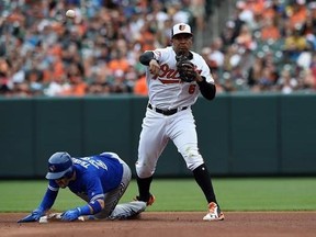 Baltimore Orioles second baseman Jonathan Schoop, right, throws to first, as Toronto Blue Jays&#039; Devon Travis slides, to complete a double play on a ball hit by Toronto Blue Jays Russell Martin in the fourth inning of a baseball game, Sunday, May 21, 2017, in Baltimore. (AP Photo/Gail Burton)
