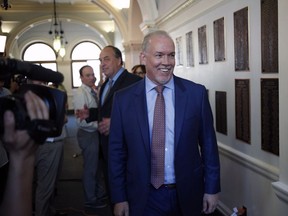 John Horgan and Andrew Weaver leave a press conference after announcing they'll be working together to help form a minority government.