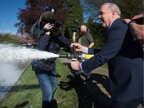 B.C. NDP Leader John Horgan tries using a fire hose after delivering doughnuts to a fire hall to mark International Firefighters Day during a campaign stop in Vancouver on Thursday.