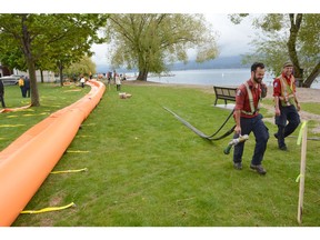 B.C. Wildfire Service workers set up aqua dams at Pritchard Park in West Kelowna on Tuesday. Work crews continue to install flood protection for rising lake levels at various locations around the Central Okanagan.