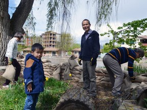 Near the mouth of Mission Creek in Kelowna, Eric Leung, aided by his parents and 4-year-old son Balin, piles sandbags to protect his neighbourhood from the slowly rising water rushing a few steps from the edge of his property.