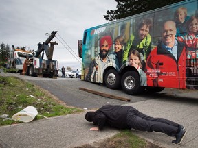 The driver of a relief bus that was called in watches as a tow truck operator tries to free NDP Leader John Horgan's campaign bus after it became stuck while trying to exit a parking lot in Surrey, B.C., on Monday May 8, 2017. A provincial election will be held on Tuesday.