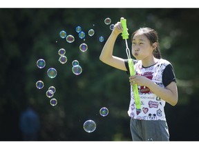 On an extra warm Sunday, Kiki Zhou blows bubbles at Westridge Park in Burnaby, B.C.