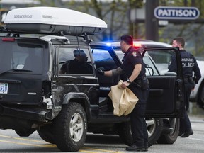 A VPD officer bags items from a black Jeep SUV boxed in by several police vehicles at E6th Ave. in Vancouver on May 2, 2017.