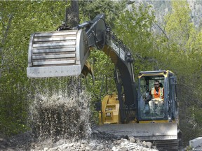 An excavator operator removes debris and junk from McDougall Creek as it crosses Shannon Lake Road on Sunday, MAY 7, 2017.