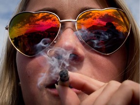 A woman smokes a joint during the annual 4-20 cannabis culture celebration at Sunset Beach in Vancouver, B.C., on Thursday, April 20, 2017.