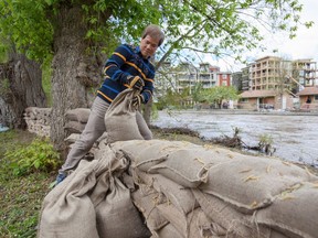 Zanjun Feng helps out with sandbagging at his son's house along Mission Creek in Kelowna B.C. on Friday, May 12, 2017. Thunderstorms and heavy rain bypassed British Columbia's Okanagan region Thursday night, sparing the flood-plagued region from further high water, but emergency officials said the danger has not passed.