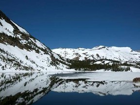 In this photo taken Tuesday, June 6, 2017, snow capped mountains are reflected by Ellery Lake near Yosemite National Park, Calif. This year&#039;s heavy snowfall has kept Highway 120 closed longer then normal, preventing visitors to the area from taking in the scenery. Crews are working overtime to clear snow from the only road through Yosemite as summer approaches, which connects the Central Valley on the west side with the Owens Valley on the east side of the Sierra Nevada. (AP Photo/Rich Pedroncel
