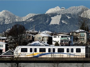 The SkyTrain travelling through Vancouver, with the North Shore mountains in the background.