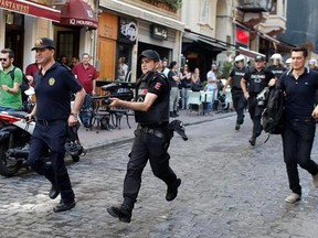 FILE - In this Sunday, June 28, 2015 file photo, Turkish police, one holding a rubber bullet rifle, center, run to disperse participants of a Pride Week march in Istanbul. For several years, Pride Week in Istanbul attracted tens of thousands of participants, making it one of largest gatherings celebrating gay, lesbian and transgender rights and diversity in the Muslim world. That changed suddenly in 2015, when authorities, citing security concerns, banned gay and trans-gender pride events chasin