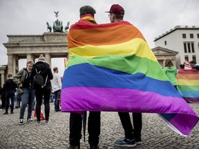 Men with rainbow flags stand in front of the Brandenburg Gate at an event organized by the SPD to celebrate the legalization of same-sex marriage in Berlin, Germany, Friday, June 30, 2017. The German Bundestag has voted to legalize same-sex marriage in the country. (Michael Kappeler/dpa via AP) ORG XMIT: FOS104