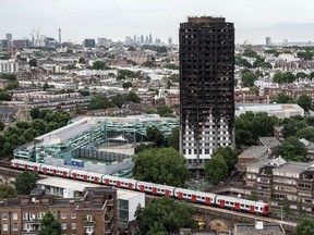 A tube train passes the remains of the Grenfell Tower, seen from a neighbouring tower block on June 26 in London. At least seventy-nine people had been confirmed dead and dozens are still missing after the 24-storey, residential tower was engulfed in flames in the early hours of June 14.