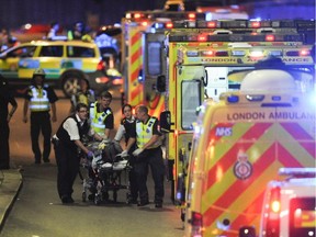 Police officers and members of the emergency services attend to a person injured in an apparent terror attack on London Bridge in central London on June 3, 2017. Armed police fired shots after reports of stabbings and a van hitting pedestrians on London Bridge on Saturday in an incident reminiscent of a terror attack in March just days ahead of a general election.