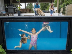 Paul Rathnam and his wife, Denise watch their three daughters, Savana, Sydney and Summer play in the Modpools, a shipping container converted into a pool/hot tub, in their Abbotsford backyard.