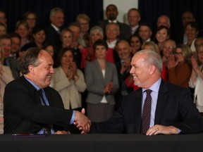 B.C. Green party Leader Andrew Weaver, left, shakes hands with NDP Leader John Horgan after signing a deal on forming a government during a news conference in the Hall of Honour at the legislature in Victoria on May 30.