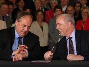 Premier John Horgan, who has promised to get big money out of B.C. politics, is hosting a $500-a-head fundraising event at Bear Mountain Resort this month that will accept union and corporate donations. B.C. NDP leader John Horgan looks on as B.C. Green party leader Andrew Weaver checks the time before signing an agreement on creating a stable minority government during a press conference in the Hall of Honour at Legislature in Victoria, B.C., on Tuesday, May 30, 2017.
