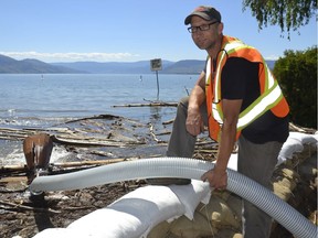 Derek Enns, a water systems operator for the City of Kelowna,   installed a larger pipe from storm drains under a sandbagged section of Bluebird Road into Okanagan Lake on Monday.