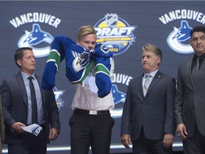 Olli Juolevi, fifth overall pick, puts on his sweater as he stands on stage with members of the Vancouver Canucks management team at the 2016 NHL draft in Buffalo.