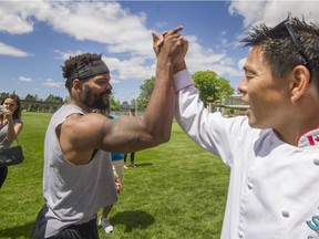 Lions Jeremiah Johnson and team dentist Dr. Greg Chang high-five as Super Chefs prepared lunch for the BC Lions at the Lions practice facility in Surrey. reporter) [PNG Merlin Archive]
Arlen Redekop, PNG